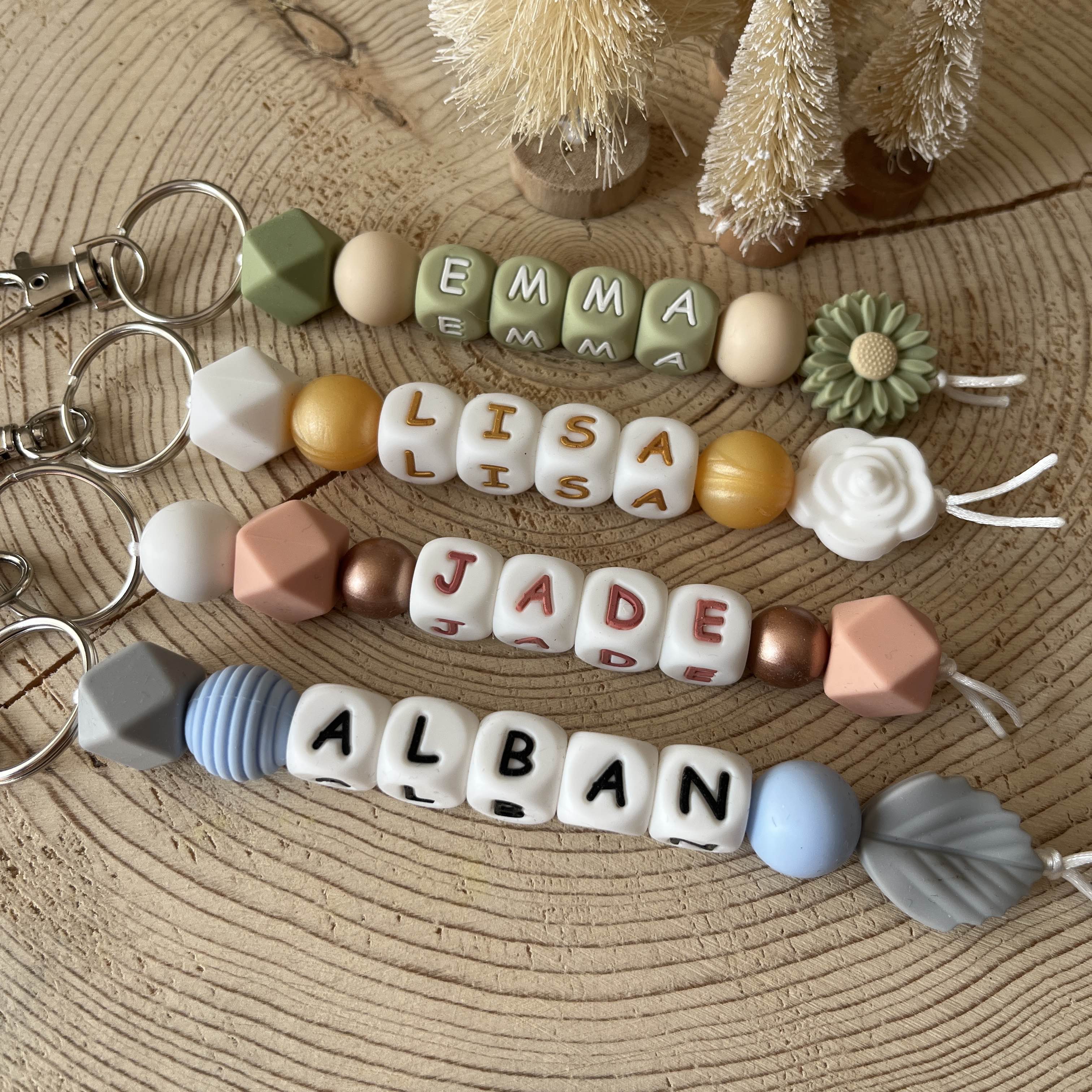 Porte-clés personnalisé en perles de silicone avec prénom, aux couleurs naturelles, présenté sur un fond en bois.