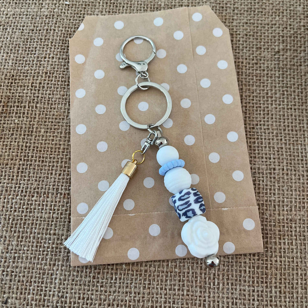 Bijou de sac en perles de silicone blanc, bleu et motif léopard, accessoire élégant pour sac à main ou trousseau de clés.