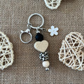 Porte-clés bijou de sac fait main en perles de silicone avec cœur beige, perle léopard, fleur blanche et mousqueton argenté.