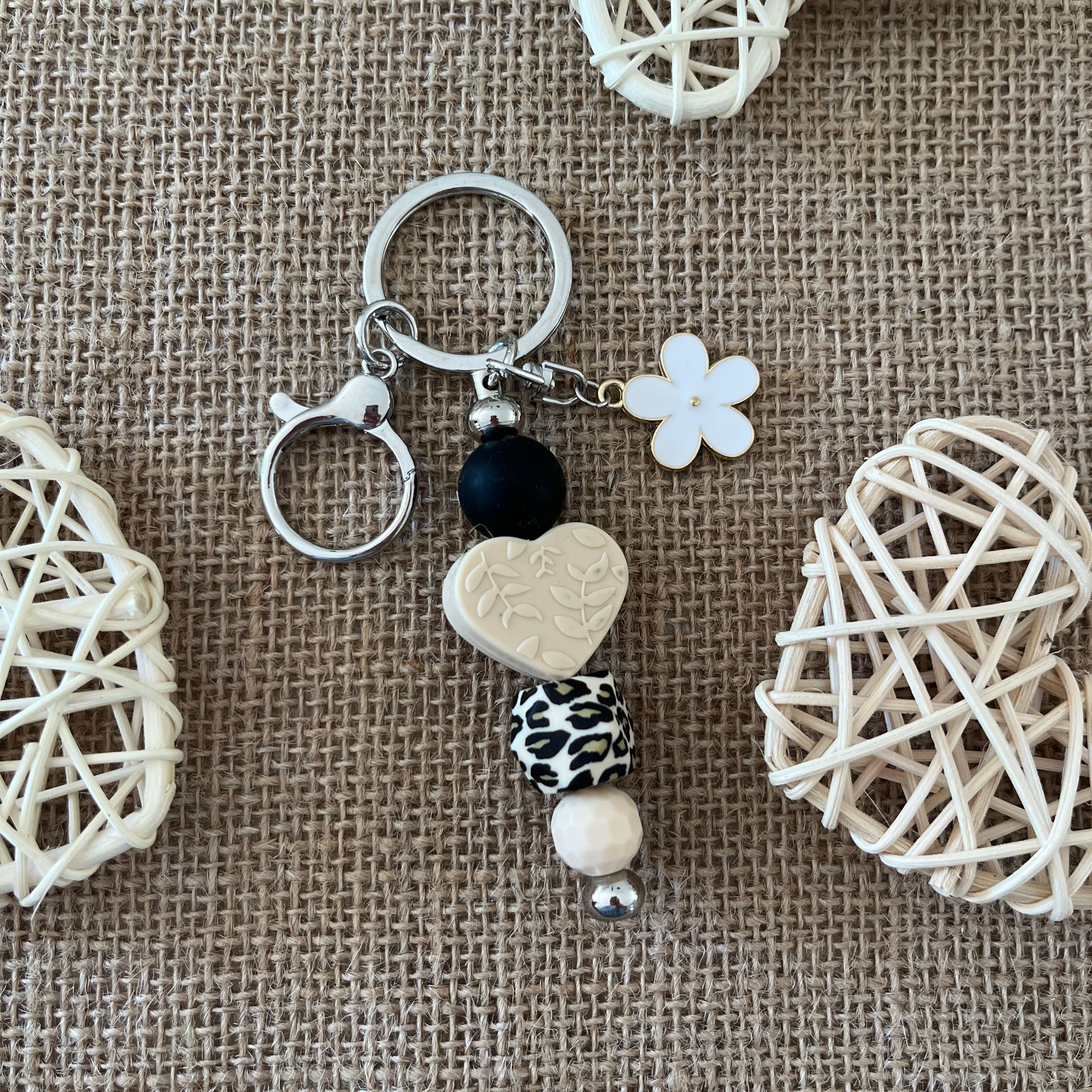 Porte-clés bijou de sac fait main en perles de silicone avec cœur beige, perle léopard, fleur blanche et mousqueton argenté.