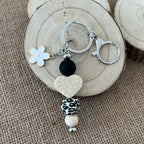 Porte-clés femme en perles de silicone avec pendentif cœur texturé, fleur blanche et perle léopard, création artisanale.