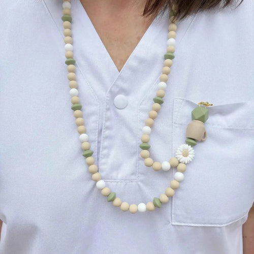 Tour de cou porte-badge en perles de silicone vert sauge et beige porté sur une tenue médicale 